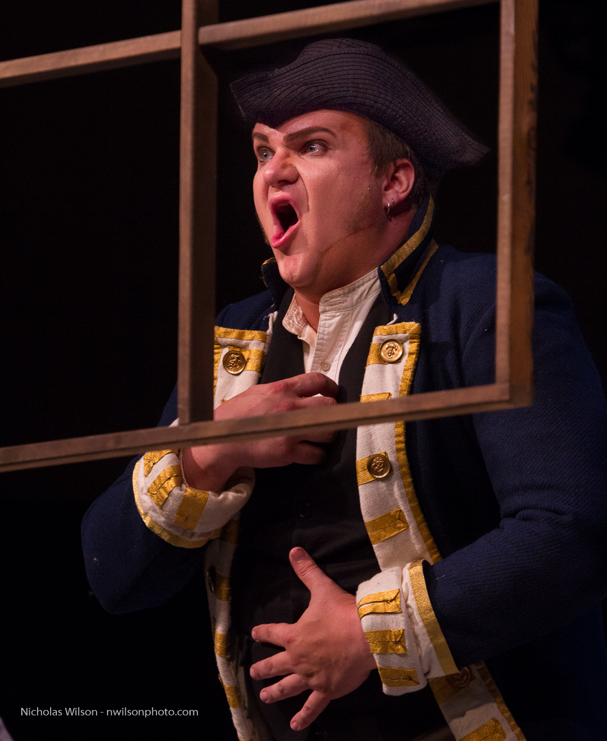 The Officer (James Russell) remains frozen in shock for several minutes as the opera continues around him