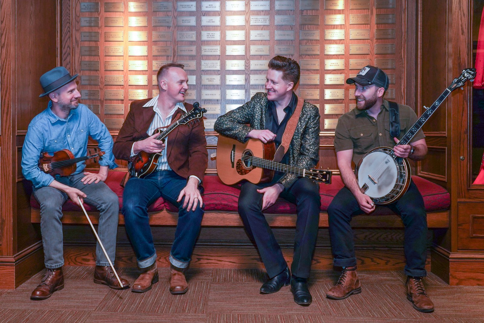 The four members of JigJam sit on a bench with their instruments.
