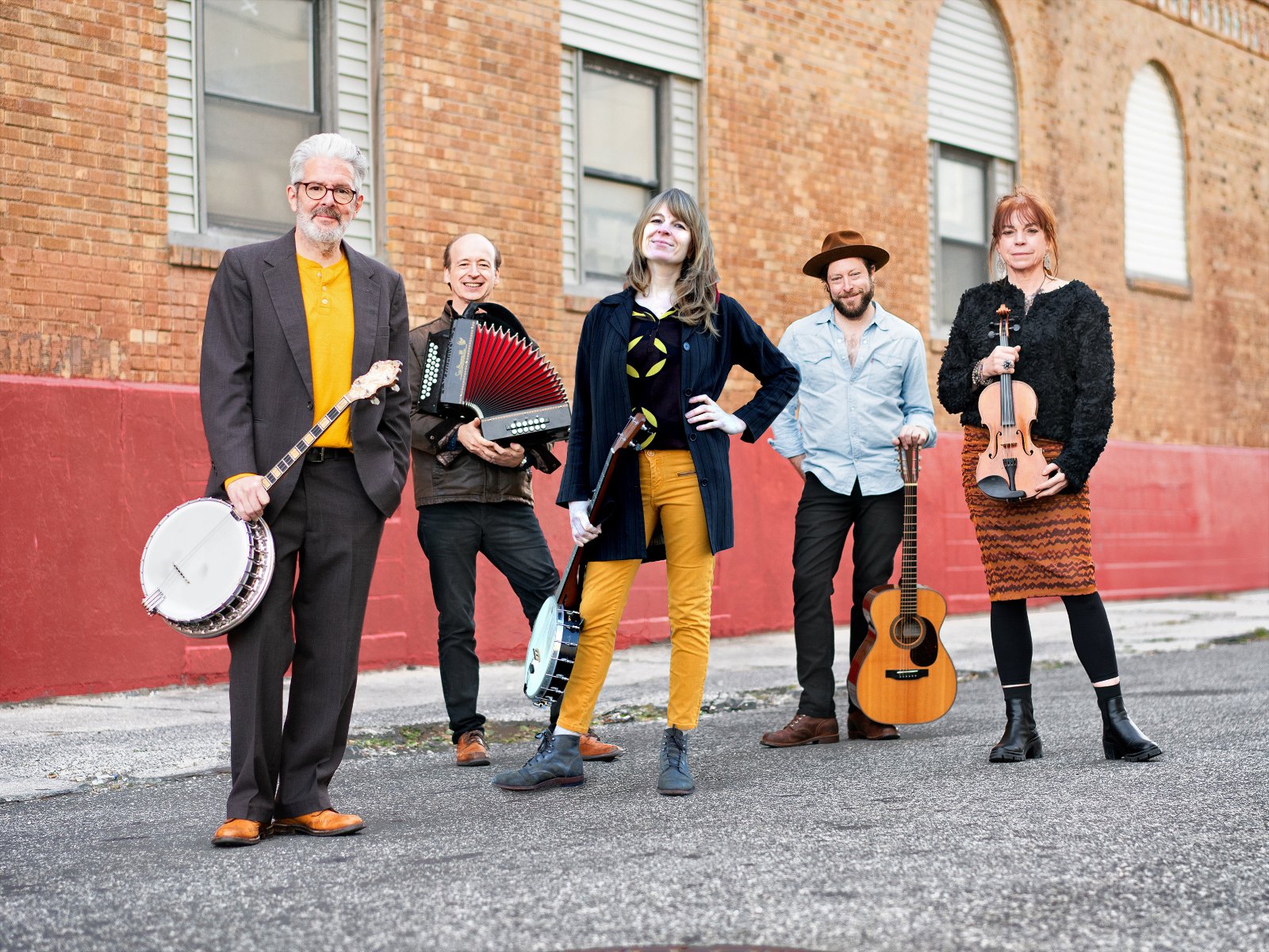 Five members of Solas pose on a paved surface holding instruments.